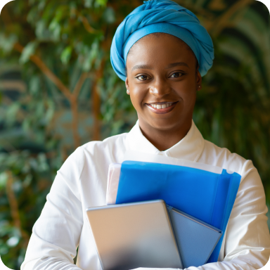 A smiling professional holding folders in front of greenery